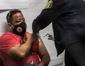 Demetrio Olivieri, a firefighter with Philadelphia’s Ladder 24, receives the first dose of the Moderna COVID-19 vaccine on Jan. 6, 2021 from Captain April Smallwood.