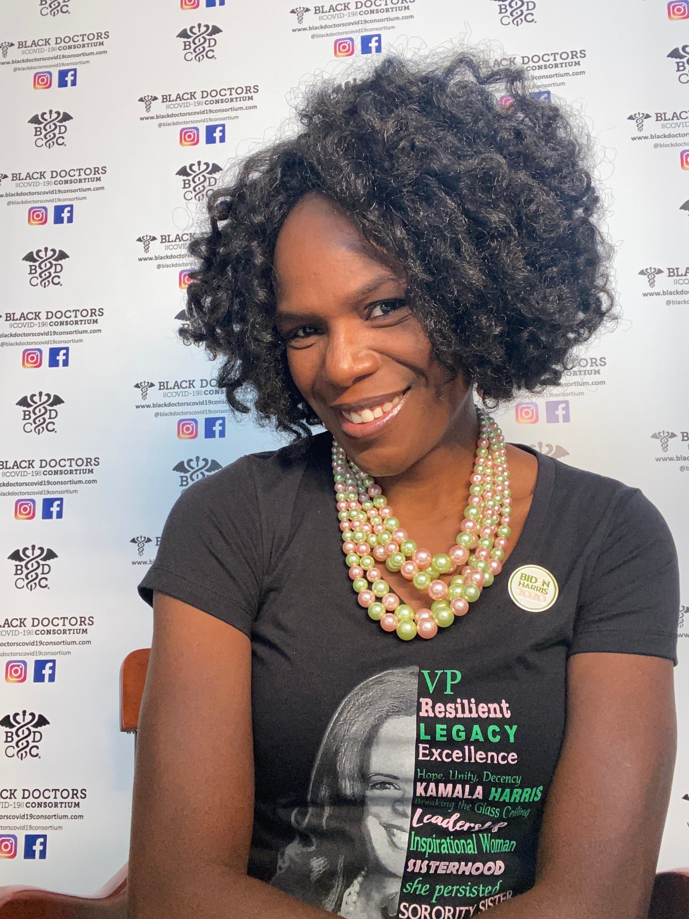 Dr. Ala Stanford wears pearls and a t-shirt that features the face of Vice President Hamala Harris