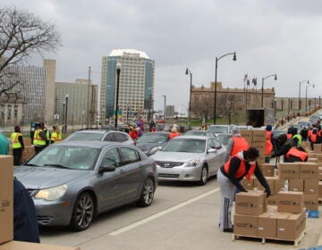 Volunteers distribute boxes of food to a long line of drivers