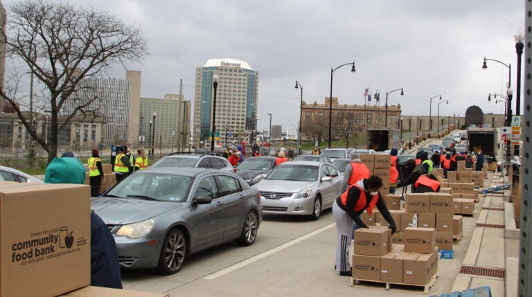 Volunteers distribute boxes of food to a long line of drivers