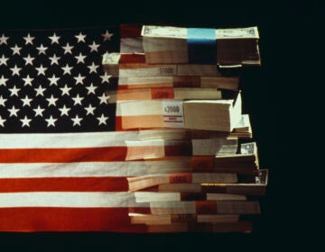 The American flag superimposed over a pile of American dollars banknotes