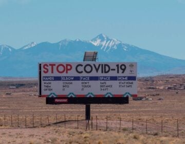 A sign warns against COVID-19 near the Navajo town of Tuba City, Ariz. As the pandemic rages across the U.S., mitigation measures continue to be critical to save lives. (Mark Ralston/AFP via Getty Images)