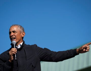 President Obama extends his arm while speaking into a microphone