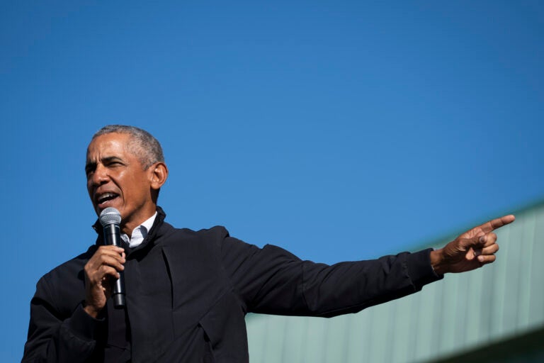 President Obama extends his arm while speaking into a microphone