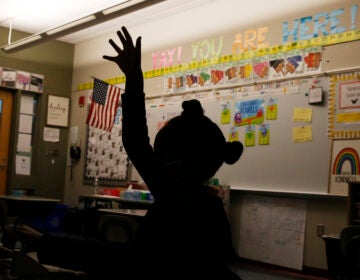 A first grade student raises her hand