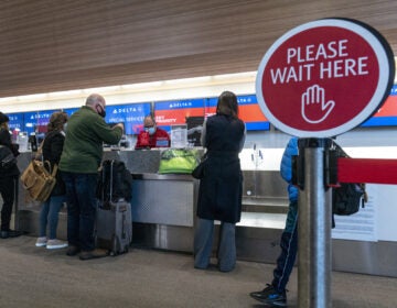 Travelers wearing protective masks check-in at the Delta Air Lines Inc. check-in counter