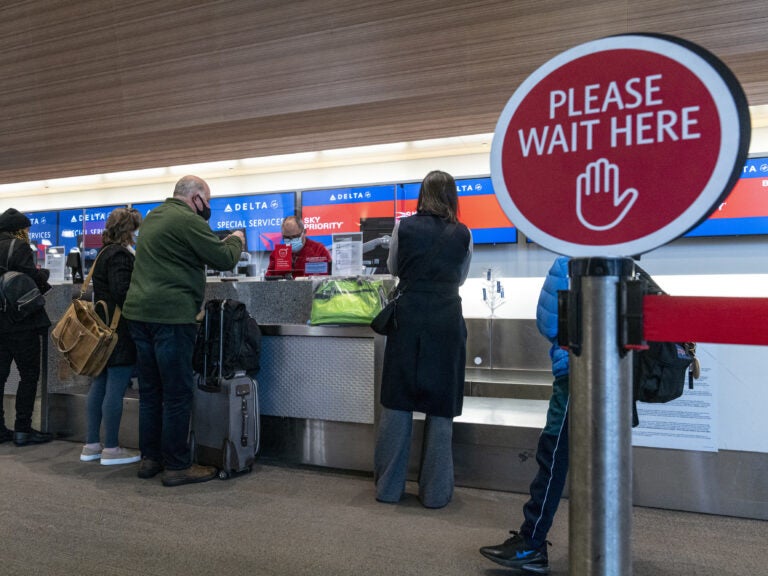 Travelers wearing protective masks check-in at the Delta Air Lines Inc. check-in counter