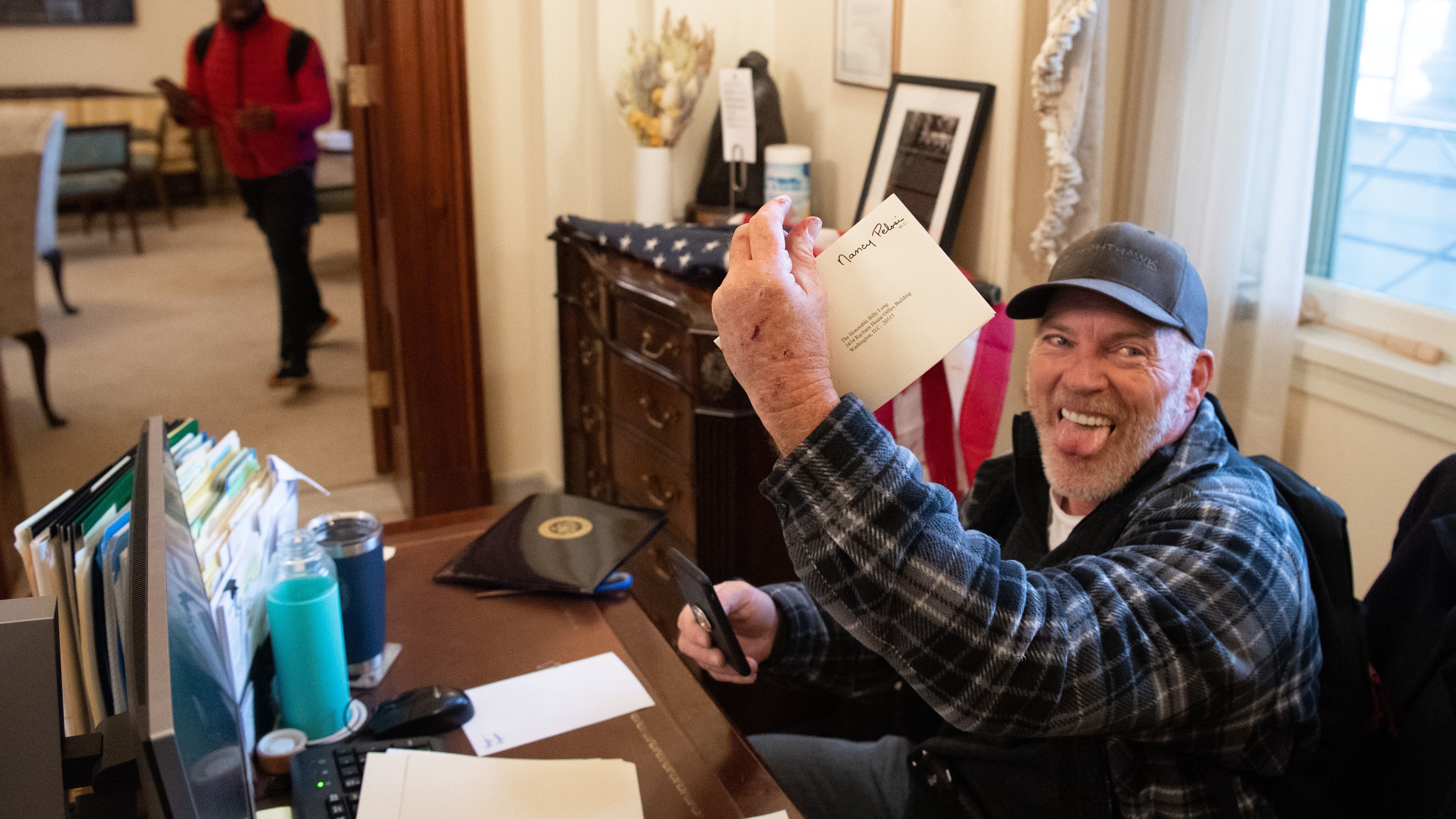 Richard Barnett holds a piece of mail as he sits inside the office of House Speaker Nancy Pelosi 