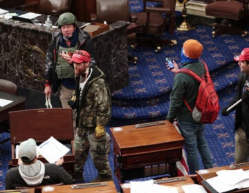 Larry Rendall Brock Jr., an Air Force veteran, is seen inside the Senate Chamber wearing a military-style helmet and tactical vest during the rioting at the U.S. Capitol. Federal prosecutors have alleged that before the attack, Brock posted on Facebook about an impending 