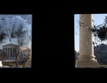 The U.S. Supreme Court is seen through a broken window at an entrance of the U.S. Capitol