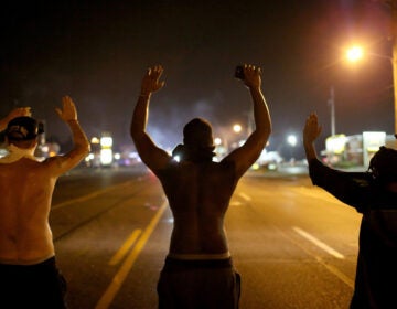 Demonstrators raise their arms and chant, 