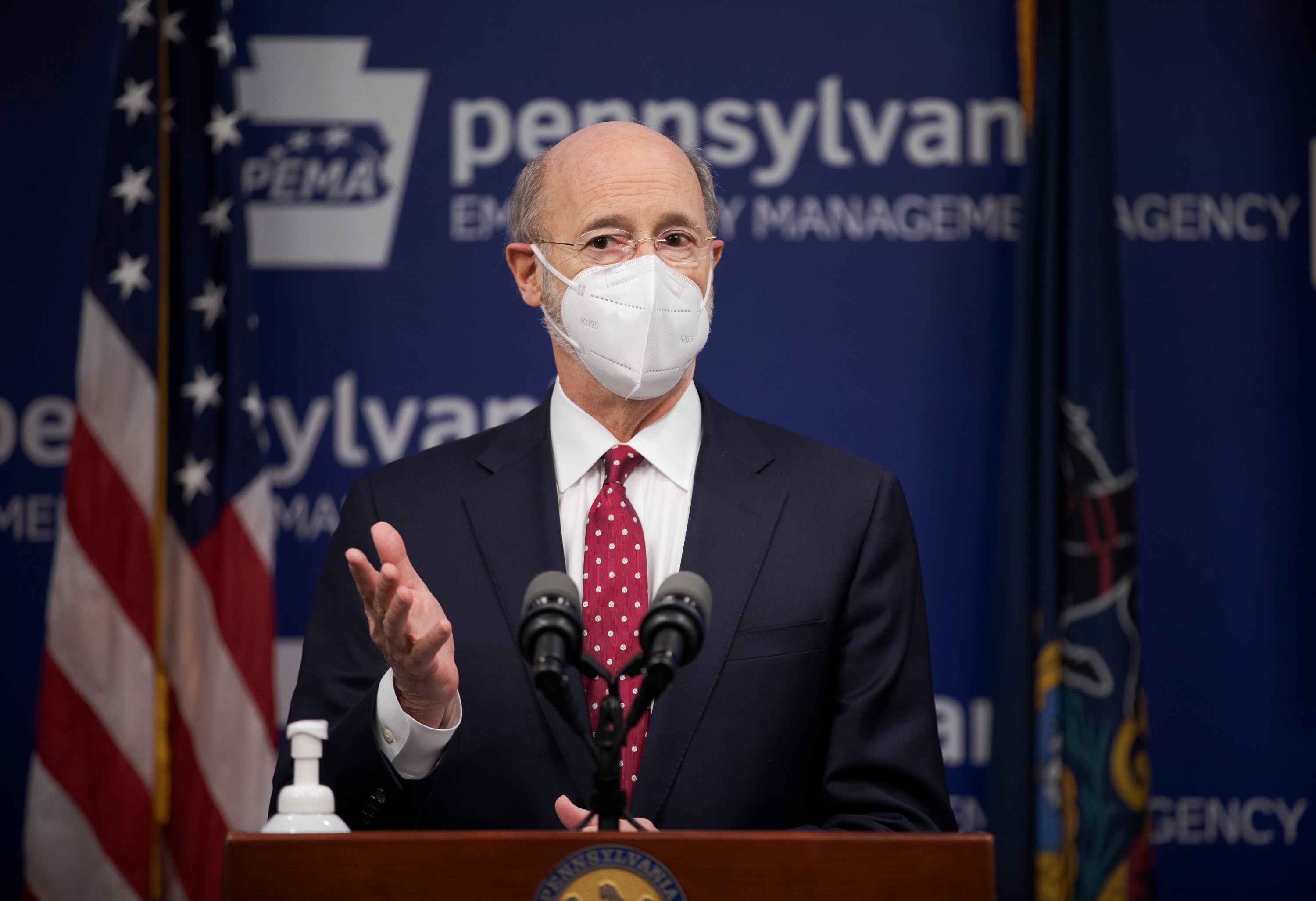 Gov. Tom Wolf, wearing a face mask, speaks to the press from behind a podium