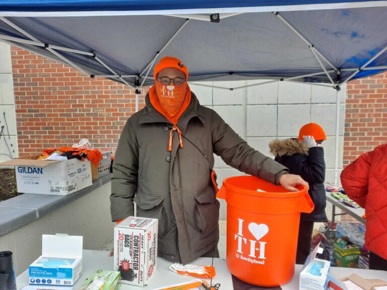 Matthew George bundled up outside in Germantown, next to a bright orange trash can