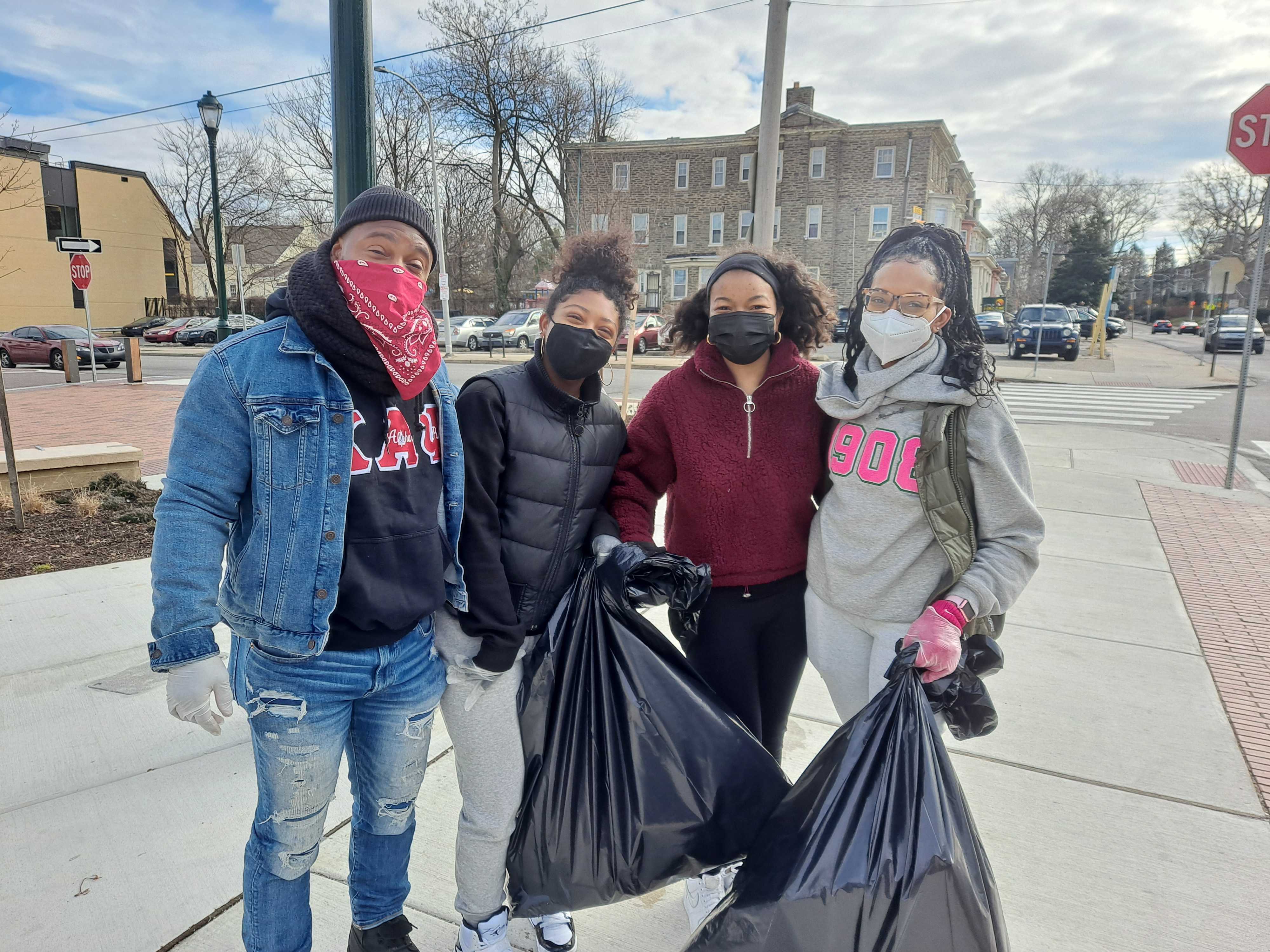 Kimberly Robinson Calland, standing with family and friends, holds a garbage bag as the group helps clean up a Germantown street