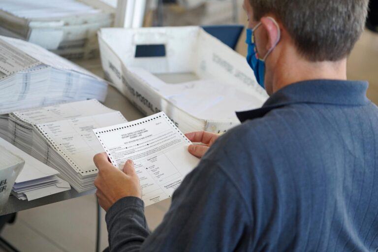 An elections worker processes a mail ballot.