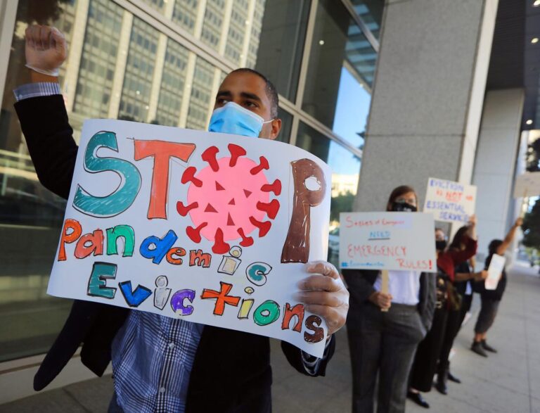 A protester wearing a face mask holds up a sign that says, 