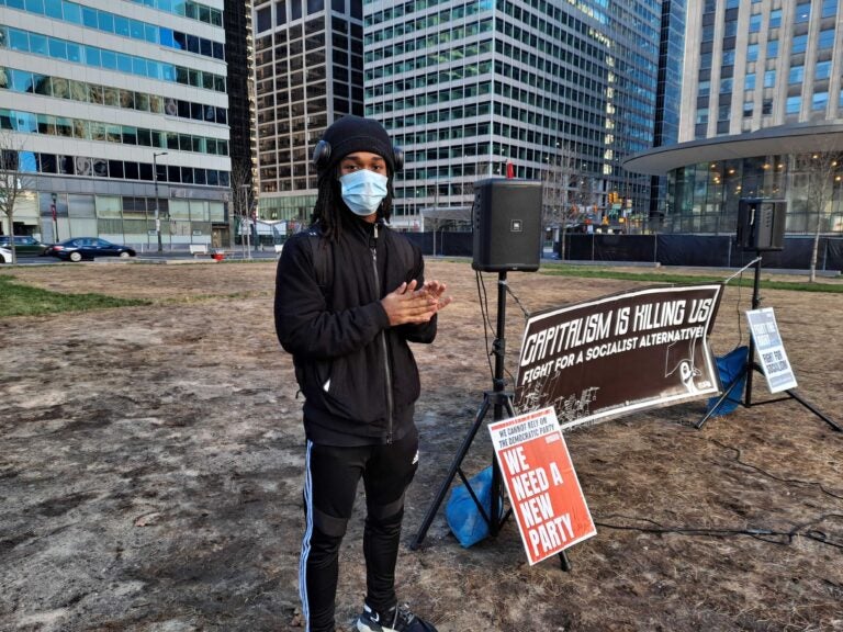 Jaja Robinson wears a face mask in front of signage at a Socialist Alternative meeting