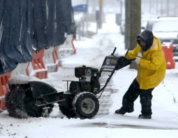 A man works to turn his snow-clearing machine
