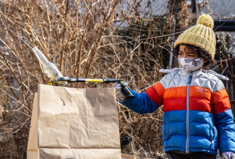 Eiji Mizukane places a glass bottle into a paper trash bag during a North Philly cleanup