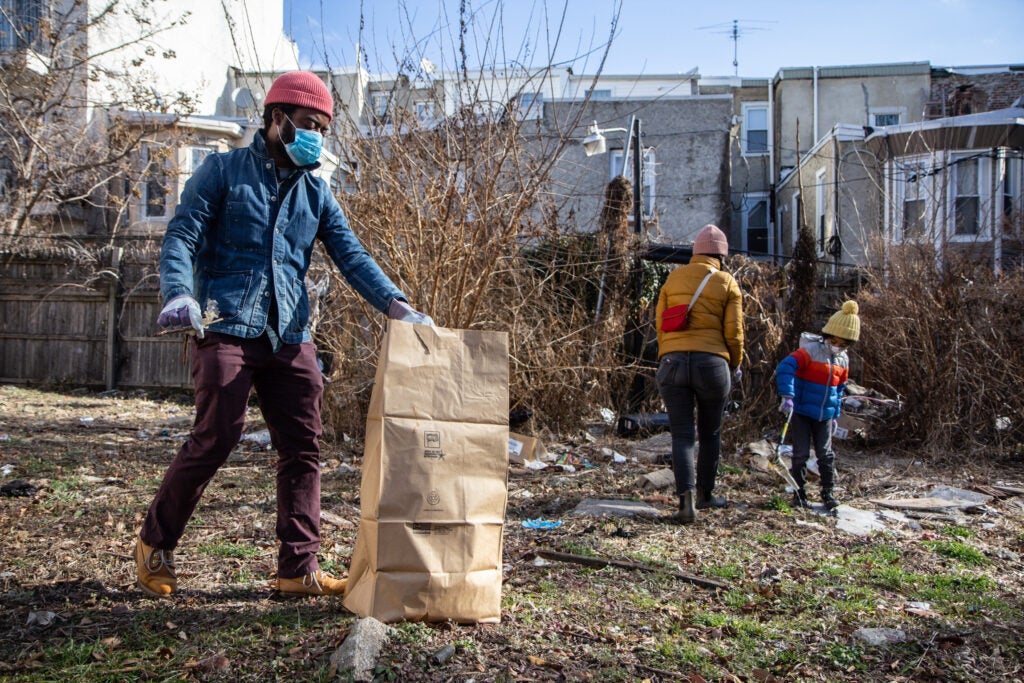 Robert Thompson (left), his wife, Eri Mizukane, and their 6-year-old son, Eiji, clean up a North Philly lot