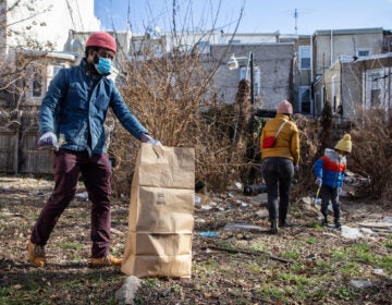 Robert Thompson (left), his wife, Eri Mizukane, and their 6-year-old son, Eiji, clean up a North Philly lot