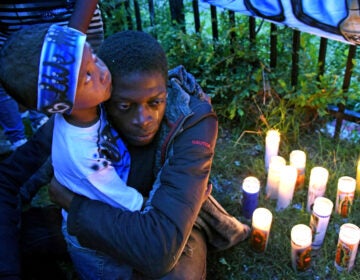 At a May 2019 vigil for Michael Thomas in Camden, Thomas' son, Major Thomas is embraced by Michael Thomas' brother, Shaqjuan Randall. (April Saul / WHYY)