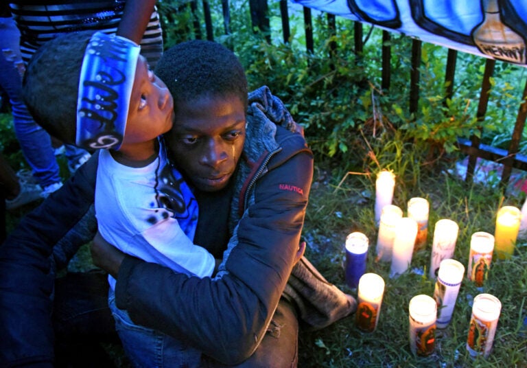 At a May 2019 vigil for Michael Thomas in Camden, Thomas' son, Major Thomas is embraced by Michael Thomas' brother, Shaqjuan Randall. (April Saul / WHYY)