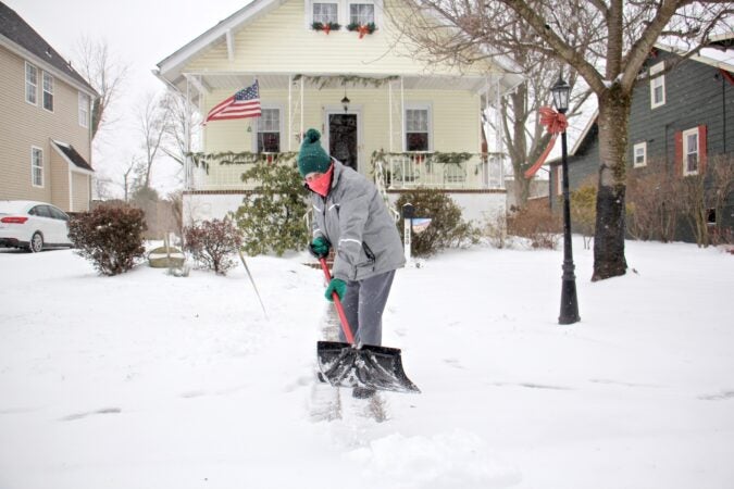A Moorestoown, N.J., resident clears the snow in front of her house