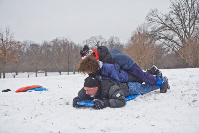 Mark Gamba, his son Luke, and friend Elias Zarin share a sled at Belmont Plateau in Philadelphia.