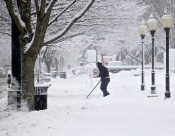 A shoveler clears the walkway to Our Lady of Good Counsel Church