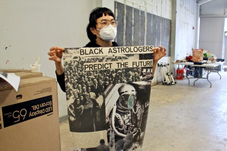 Anne Ishii holds up a poster at an exhibit