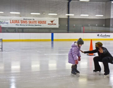 Skate instructor Sultana Afifiah helps a new skater at Laura Sims Skatehouse in Philadelphia. The city’s rinks are reopening with COVID restrictions in February. (Kimberly Paynter/WHYY