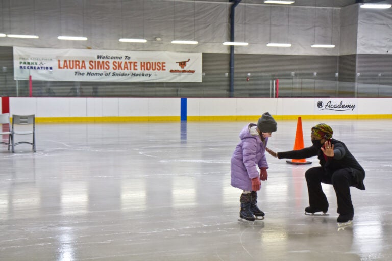 Skate instructor Sultana Afifiah helps a new skater at Laura Sims Skatehouse in Philadelphia. The city’s rinks are reopening with COVID restrictions in February. (Kimberly Paynter/WHYY