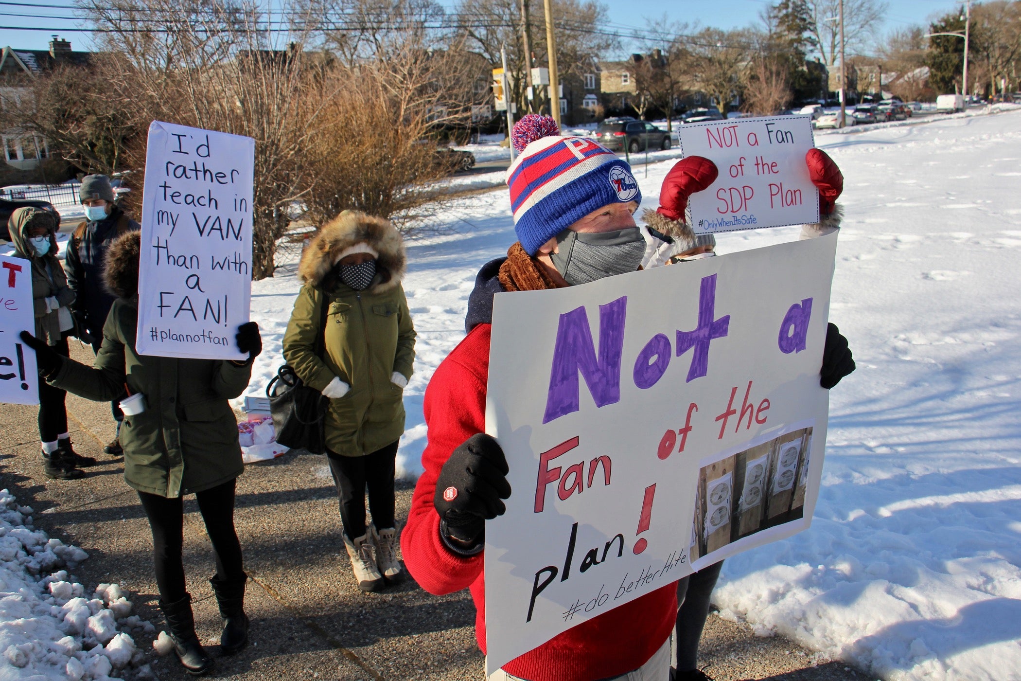 Teachers hold signs outside Gompers School in protest of the district's plan to return to in-person learning