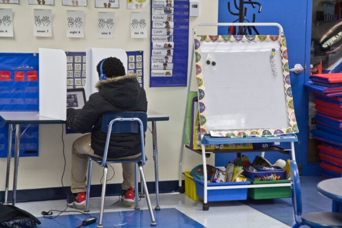 A student sits at a desk with physical barriers placed on either side