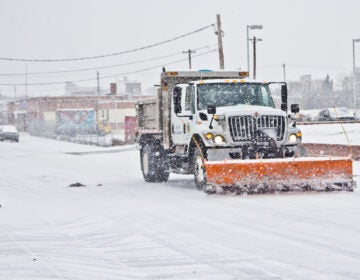 A city trash truck outfitted with a plow rolls down Cumberland Street