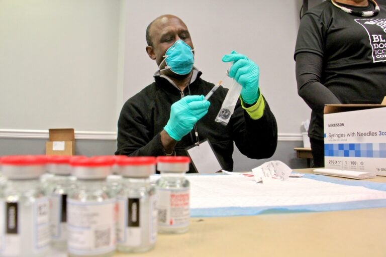 Dr. Christophe DeBrady of the Black Doctors COVID-19 Consortium prepares doses of vaccine for the hundreds who turned out for a mass vaccine clinic at the Liacouras Center at Temple University. (Emma Lee/WHYY)