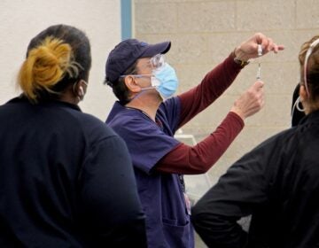 A staff member demonstrates how to prepare a dose at Philadelphia's COVID-19 vaccine center