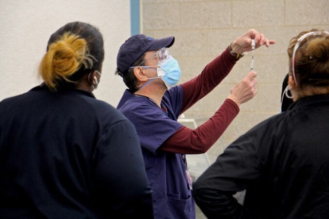 A staff member demonstrates how to prepare a dose at Philadelphia's COVID-19 vaccine center