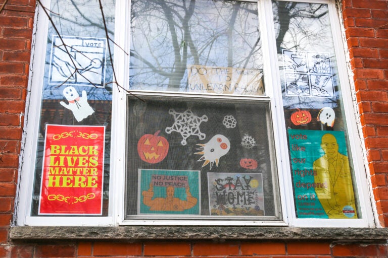 A Philadelphia household mixes political signs and holiday decor in their front windows during the turbulent fall of 2020. (Conrad Benner for WHYY)