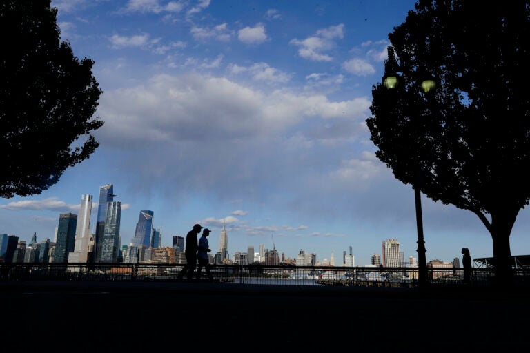 Pedestrians walk in Maxwell Place Park in view of midtown Mahattan Thursday, May 7, 2020, in Hoboken, N.J. (AP Photo/Frank Franklin II)