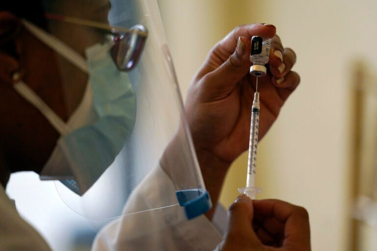 A worker prepares a syringe with the COVID-19 vaccine