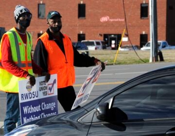 Tray Ragland, left, and Kim Hickerson of the Retail, Wholesale and Department Store Union hold signs outside an Amazon facility where labor is trying to organize workers on Tuesday, Feb. 9, 2021. (AP Photo/Jay Reeves)