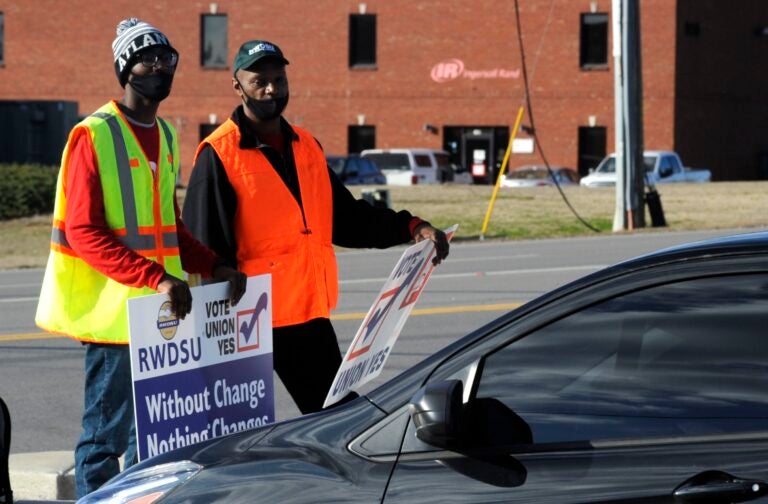 Tray Ragland, left, and Kim Hickerson of the Retail, Wholesale and Department Store Union hold signs outside an Amazon facility where labor is trying to organize workers on Tuesday, Feb. 9, 2021. (AP Photo/Jay Reeves)