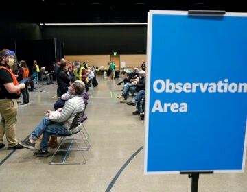 In this  Jan. 24, 2021, file photo, a worker at left checks in with people sitting in an observation area after they were given the first of two doses of the Pfizer vaccine for COVID-19 in Seattle. (AP Photo/Ted S. Warren)