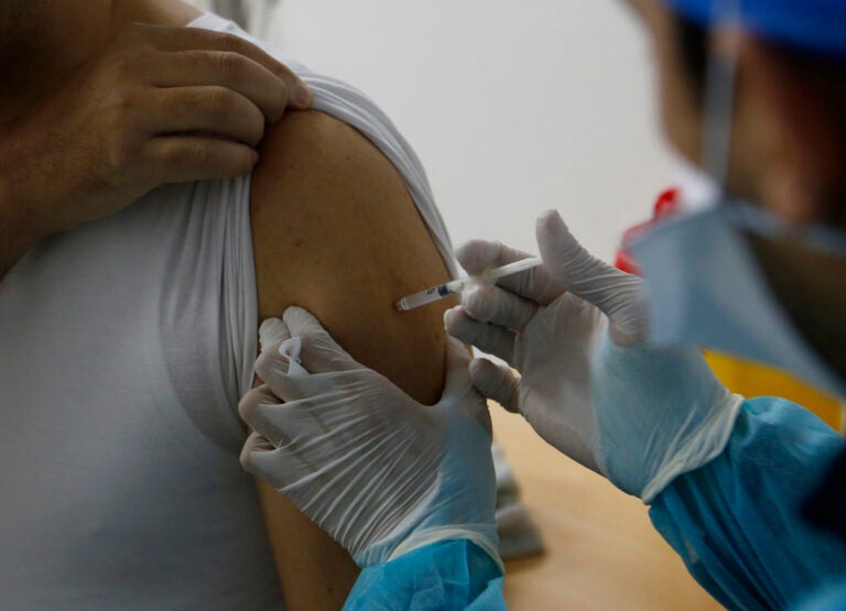 A nurse administers the COVID-19 vaccine to a health worker.