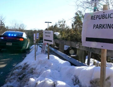 A sign directs Republican and Democrat legislators to their parking areas as a N.H. State Trooper watches the flow of traffic prior to a New Hampshire House of Representatives session held at NH Sportsplex, due to the coronavirus, Wednesday, Feb. 24, 2021, in Bedford, N.H. (AP Photo/Charles Krupa)