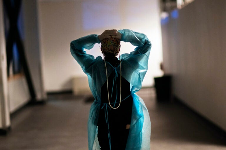 A nurse walks down a hallway with her arms in the air, clasping the back of her head