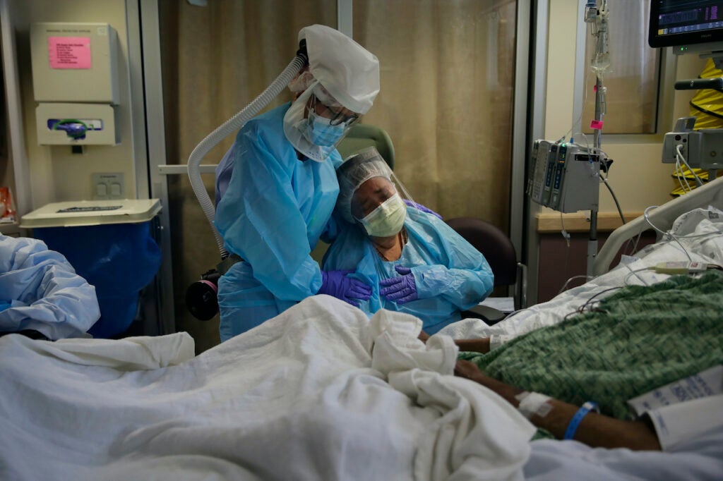 Romelia Navarro, right, is comforted by nurse Michele Younkin, left, as she weeps while sitting at the bedside of her dying husband