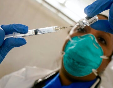 A doctor extracts COVID-19 vaccine out of a vial